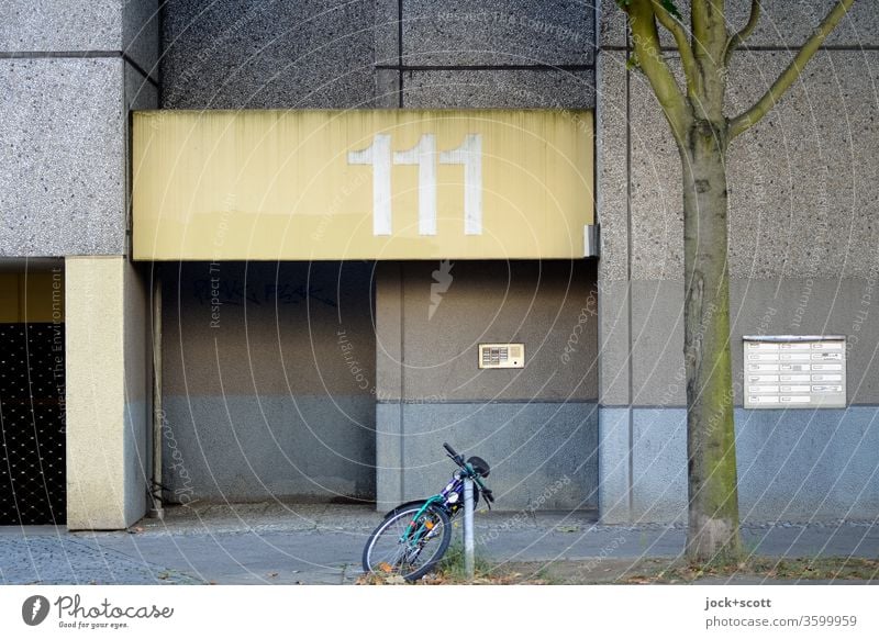 Hausnummer 111, Zahl der Engel Fassade Eingang Architektur Plattenbau klingeln Briefkasten trist verwittert Zahn der Zeit Gedeckte Farben Fahrrad Bürgersteig