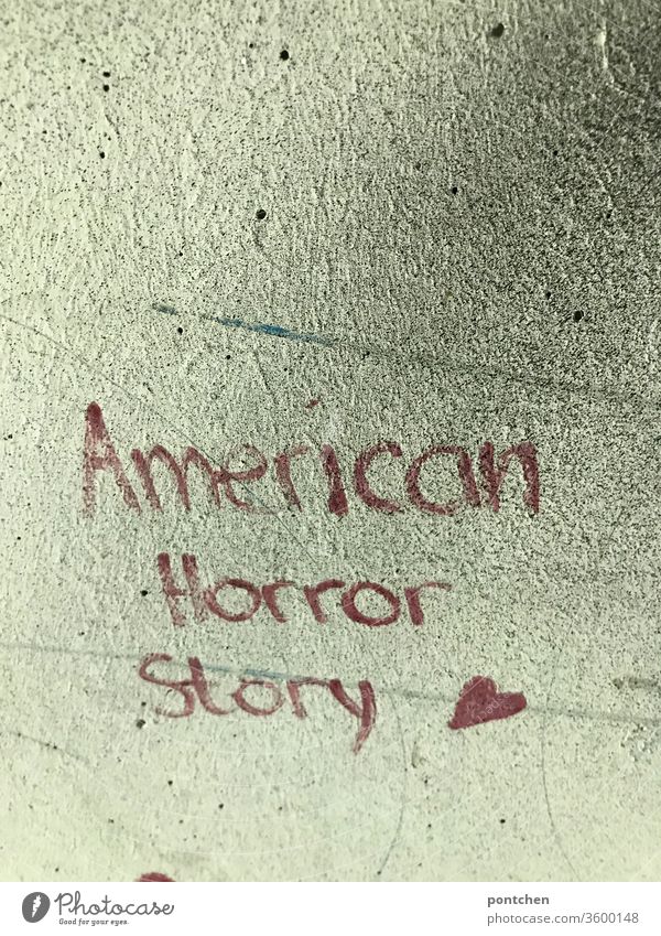 American Horror Story steht mit roter Schrift auf einer Hauswand. Politik, USA, krise. Filmtitel. Trump American Horror story politik trump weltgeschehen