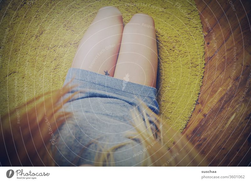 auf dem boden sitzend auf die eigenen beine gucken | symmetrie Frau weiblich Beine feminin Teppich auf dem Fußboden Haare Holzboden Tattoo Stern Symmetrie