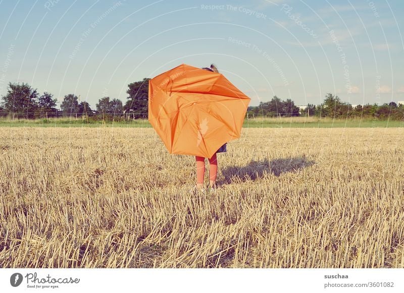 kind auf einem strohacker mit kaputtem regenschirm Kind Regenschirm orange Acker Feld Strohfeld Getreidefeld Landwirtschaft Landschaft Ackerwirtschaft Sommer