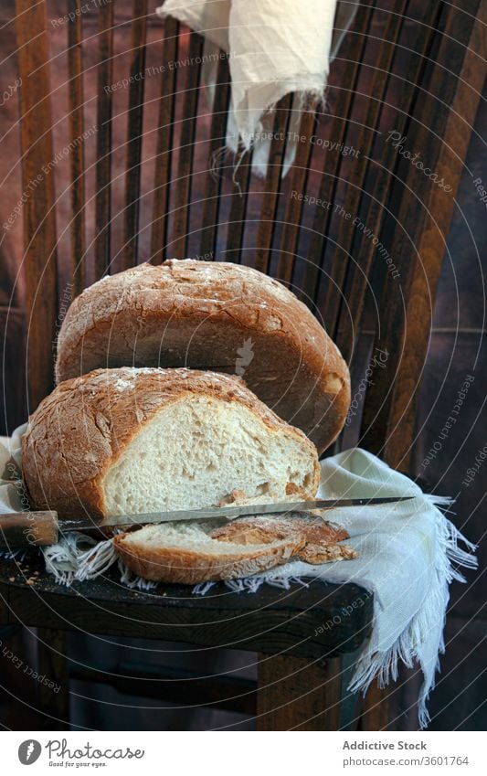 Frisch gebackenes Brot auf Serviette Brotlaib frisch Bäckerei lecker geschmackvoll selbstgemacht Spielfigur aromatisch Messer stechend hölzern Stuhl