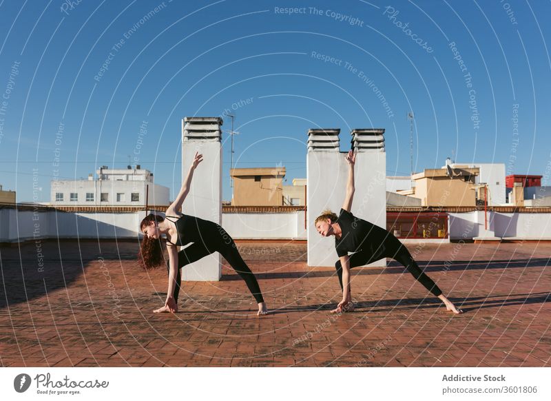 Frauen, die Twist-Yoga praktizieren, posieren auf dem Dach Zusammensein üben gedrehtes Dreieck parivrtta trikonasana Pose verdrehen stehen Dachterrasse