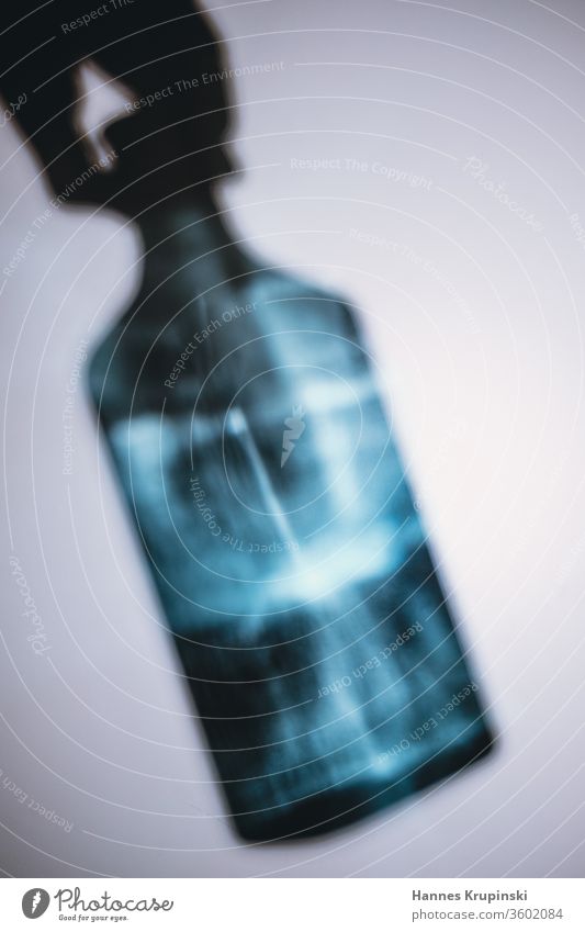 Griff zur Flasche Gin blau Lichtspiel Schatten Hand festhalten Glas Getränk Alkohol trinken
