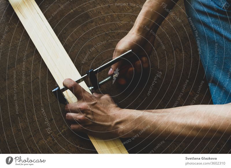 Männerhände befestigen die Klemme an den Holzschienen und nehmen vor dem Schneiden eine Messung vor. Reparatur-Konzept Werkzeug heimwärts Arbeit Konstruktion