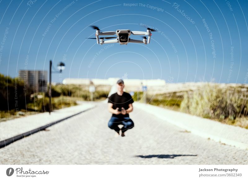 Mann, der zusammen mit seiner Drohne das Fernfliegen festhält Dröhnen Fliege Flug Hubschrauber Technik & Technologie Konzept aladin Fröhlichkeit sonnig Straße