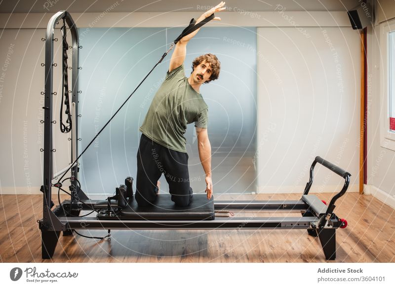 Sportlicher Mann benutzt Pilates-Reformer während des Trainings Dehnung sportlich Sportkleidung widersetzen Band Maschine Sportler Athlet Übung Fitness