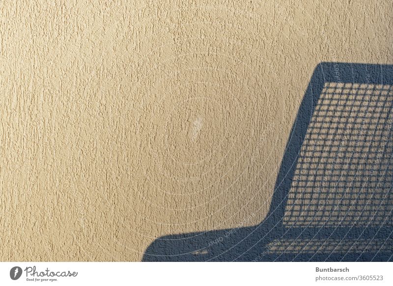 Schatten einer Sitzbank aus Metall an einer Rauhputzwand Bank Wand Menschenleer rauhputz Putz Mauer Farbfoto Textfreiraum unten Außenaufnahme weiß blau
