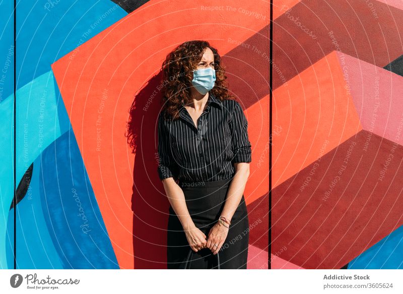 Frau mit Gesichtsmaske vor einer Wand mit leuchtenden Farben. Seuche Menschen Mundschutz Coronavirus Virus Schutz Grippe covid-19 krank Krankheit Gesundheit