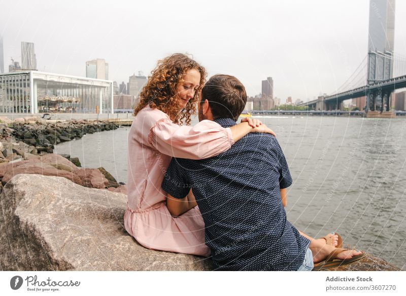 Zärtliches Paar küsst sich am Flussufer in New York Partnerschaft Zusammensein Kuss romantisch Umarmung Brooklyn Bridge Angebot schlendern New York State
