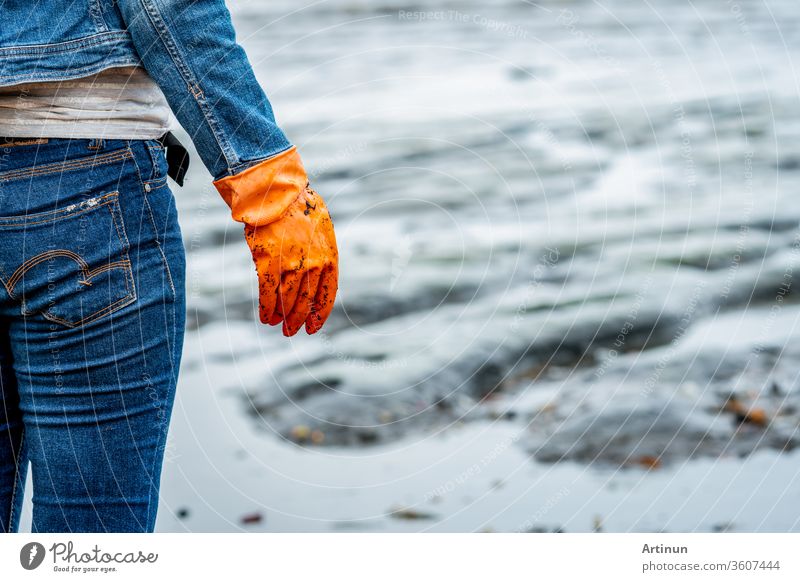 Die Freiwilligen tragen Jeans und langärmelige Hemden und tragen orangefarbene Gummihandschuhe, um den Müll am Strand zu sammeln. Strandumgebung. Frau, die den Strand säubert. Frau, die den Müll am Strand aufräumt.