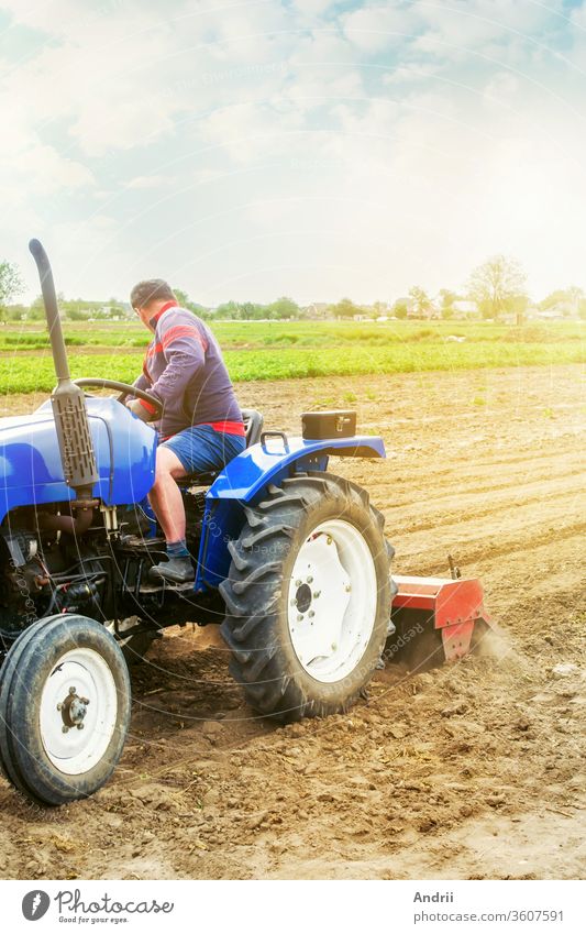 Ein Landwirt auf einem Traktor bearbeitet ein Feld. Der Boden wird gemahlen, zerkrümelt und gemischt. Landwirtschaft, Anbau von Bio-Gemüse. Lockern der Oberfläche, Kultivieren des Bodens für weitere Anpflanzungen.
