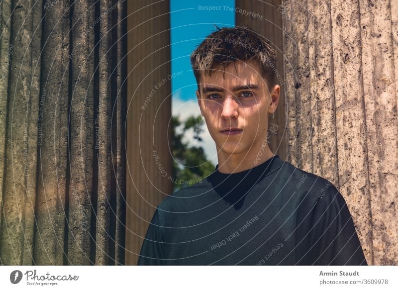 Porträt eines jungen Mannes, der zwischen antiken Säulen steht Teenager männlich im Freien Ständer Architektur schön schwarz blau Junge lässig Kaukasier