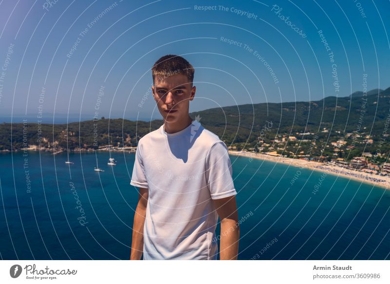 Porträt eines selbstbewussten jungen Mannes mit dem Strand der Stadt Parga im Hintergrund schön blau Junge lässig Kaukasier wolkenlos Reise Lifestyle Blick