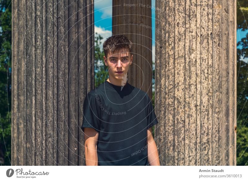 Porträt eines jungen Mannes, der zwischen antiken Säulen steht Architektur schön schwarz blau Junge lässig Kaukasier Kleidung Konzentration selbstbewusst Reise