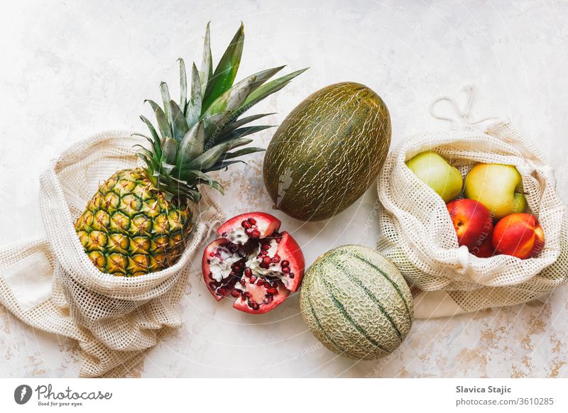 Frische Früchte der Saison (Ananas, grüne Äpfel, Granatapfel, Pfirsiche und Melone) in umweltfreundlichen und wiederverwendbaren Einkaufsnetztaschen. Gesunde vegane Ernährung. Null Abfall
