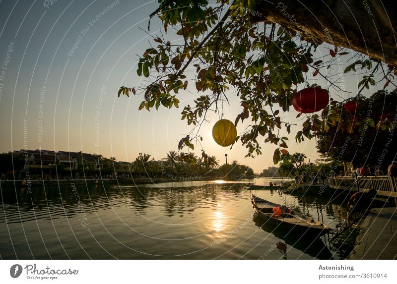 Abendlicht mit Laternen am Fluss in Hoi An, Vietnam Sonne Sonnenlicht Boot Ruderboot Baum Blätter Himmel Natur Dämmerung Thu Bon Wasser Spiegelung gelb rot bunt