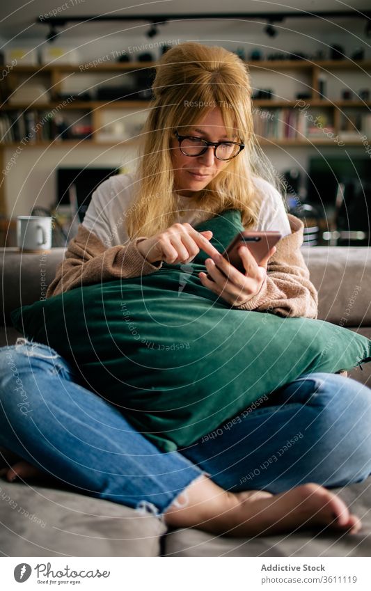 Nutzpflanzenfrau surft zu Hause auf einem Smartphone Browsen Frau heimwärts Surfen Funktelefon Wochenende unterhalten benutzend Touchscreen gemütlich Gerät