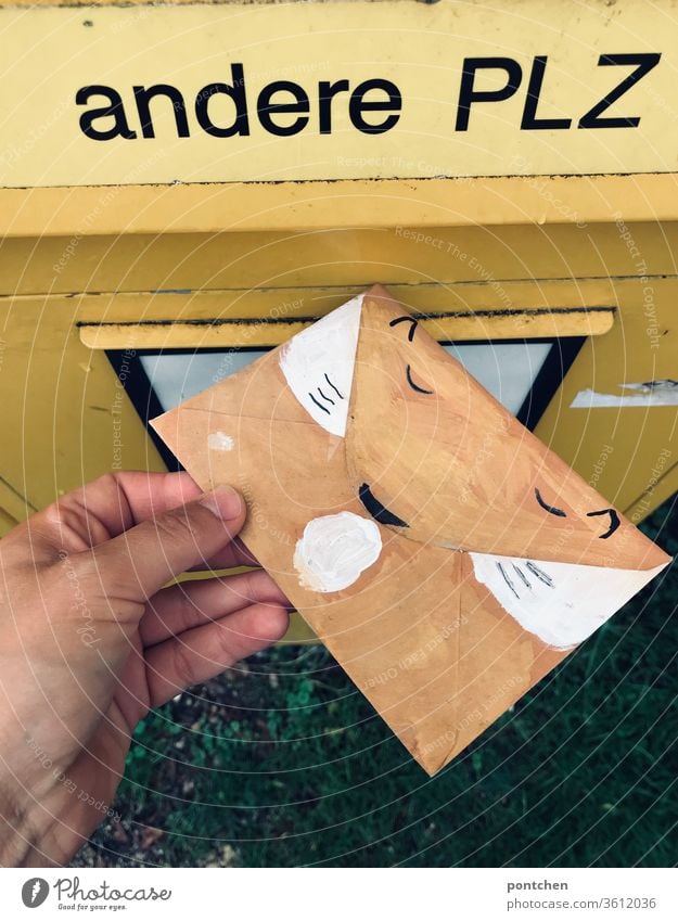 Hand wirft einen als Fuchs bemalten umschlag in den BriefSchlitz für andere Postleitzahlen des Briefkasten. Einladung zum Kindergeburtstsg Beschriftung