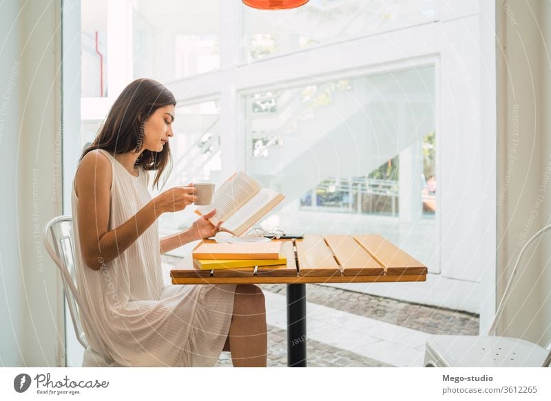 Junge Frau liest in einem Café ein Buch. Sitzen lesen Werkstatt Kaffee entspannend Hobby ernst Kultur Kaffeepause Kaukasier Blick besinnlich Lehrbuch Porträt