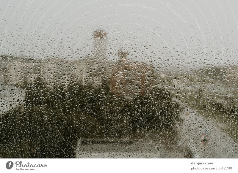 Nasses Fenster vor dem Hintergrund eines abendlichen Ausblicks auf die Stadt Regentropfen Wasser abstrakt nass Textur Natur Glas Wetter regnerisch aqua