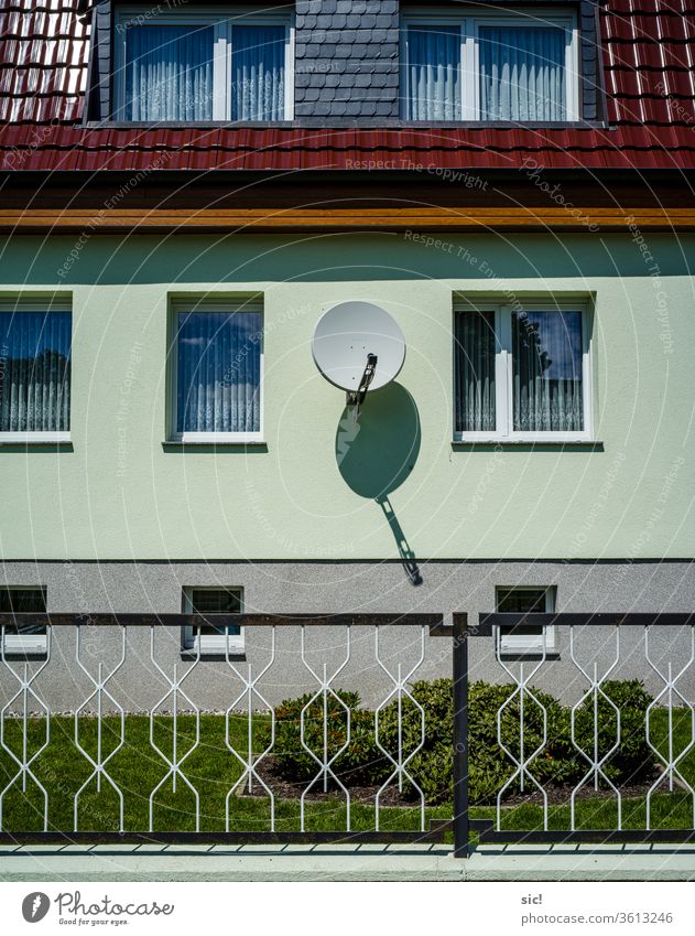 Satellitenschüssel an Hauswand Architektur Gebäude Fenster Fassade Menschenleer Außenaufnahme Wand Mauer Zaun Grün Rot Fernsehempfang Farbfoto blau Schatten