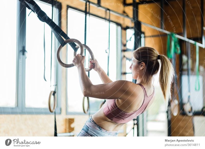 Junge sportliche Frau trainiert auf Gymnastikringen muskulös Waffen Beteiligung im Innenbereich passen Fitness Sport zäh Ausdauer eine Menschen fokussiert Kraft