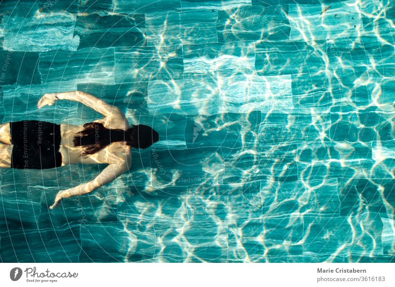 Ein Mann, der allein im Schwimmbad schwimmt, zeigt das Konzept, sich in der neuen normalen Lebensweise aufgrund der Covid-19-Pandemie fit zu halten