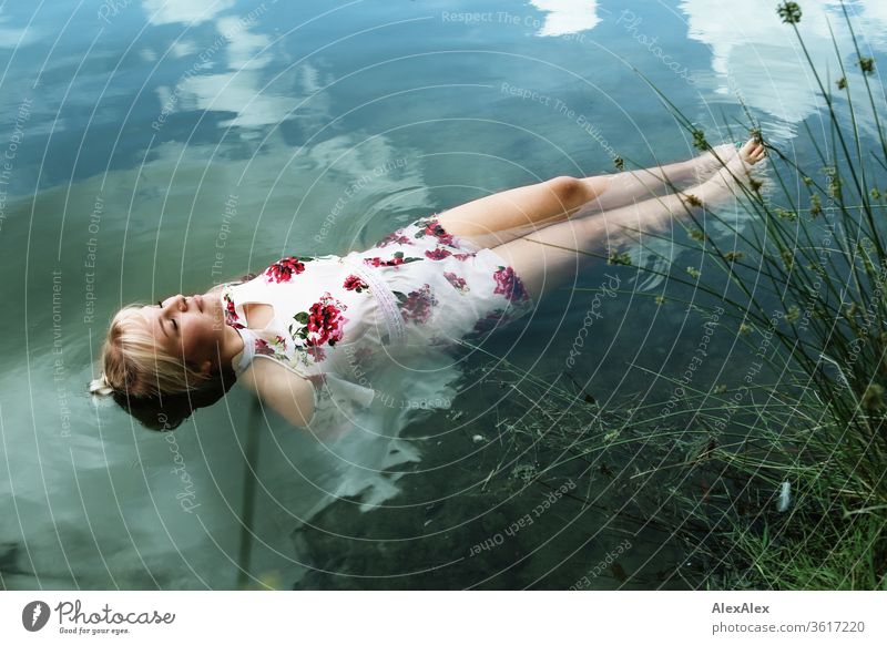 Portrait einer jungen blonden Frau die in einem weißen Sommerkleid in einem See an der Oberfläche Mädchen junge Frau schön lange Haare 19 18-20 Jahre