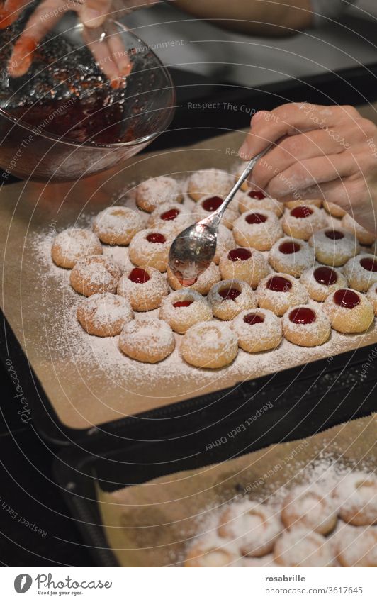 Weihnachtbäckerei: Hände einer Frau füllen mit einem Teelöffel Johannisbeergelee in Engelsaugen, auch Husarenkrapfen genannt | Vorfreude Plätzchen Weihnachten