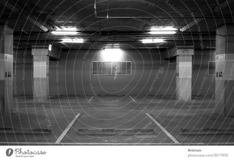 Perspektivische Ansicht eines leeren Innenparkplatzes am Einkaufszentrum. Unterirdischer Betonparkplatz mit offenem Licht. Trauriges und einsames Konzept. Parkplätze Q43 und Q44 am Block B2