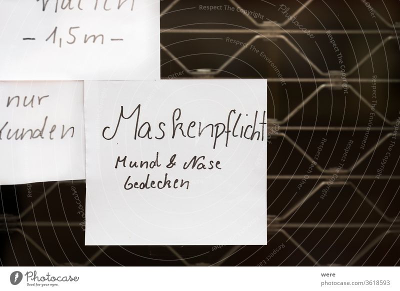 handgeschriebenes Türschild auf einer Eisengittertür mit deutschem Text Maskenpflicht Mund und Nase bedecken Deutscher Text Regelung Korona Deckung Seuche
