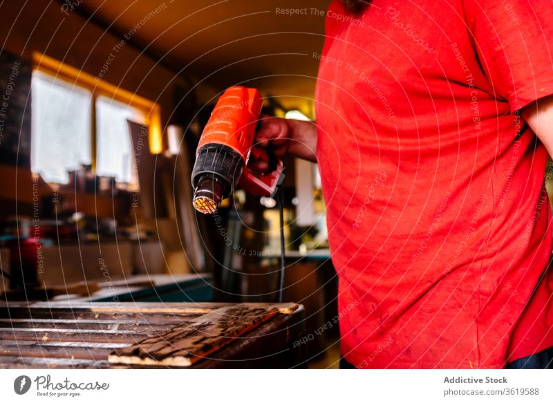 Ernte-Holzarbeiter mit Heißluftpistole in der Werkstatt erwärmen Pistole Schreinerei Tischlerin Mann trocknen Zimmerer Holzarbeiten professionell männlich