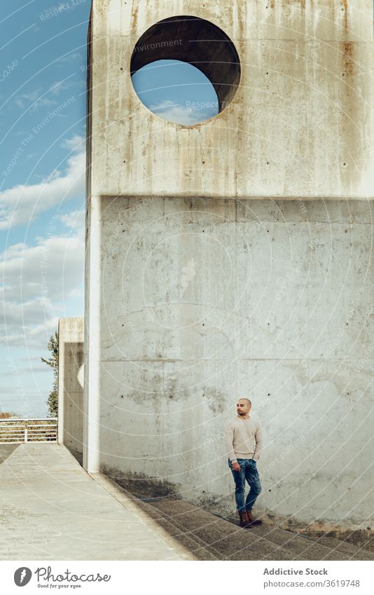 Mann steht auf Treppe in der Nähe einer schäbigen Mauer Stein Konstruktion Wand urban allein Hipster modern Beton Typ lässig männlich Straße Grunge verwittert