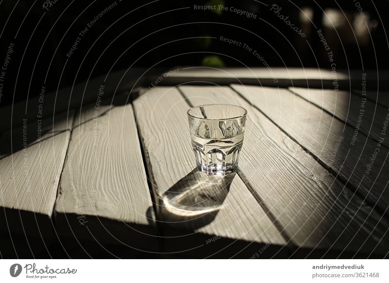 ein Glas Wasser auf einem weißen Tisch mit Sonnenstrahlen vor dem Hintergrund der Natur übersichtlich Licht Strahlen Holz frisch Sauberkeit Frische trinken rein
