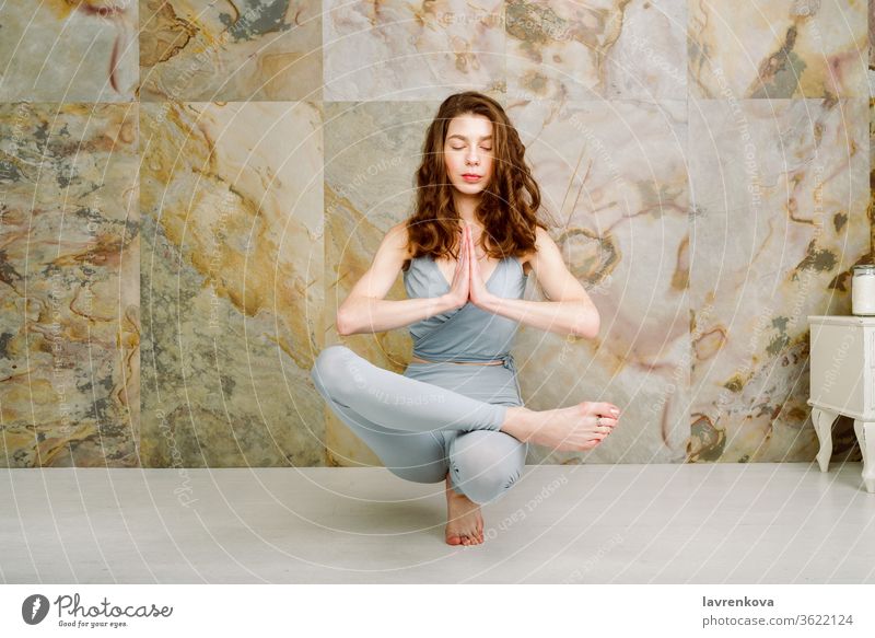 Junge Frau übt Zehenstand (Padangusthasana) Posieren im Haus, selektiver Fokus Yoga Training Sport aktiv yogini Asana sportlich schlank dünn im Innenbereich
