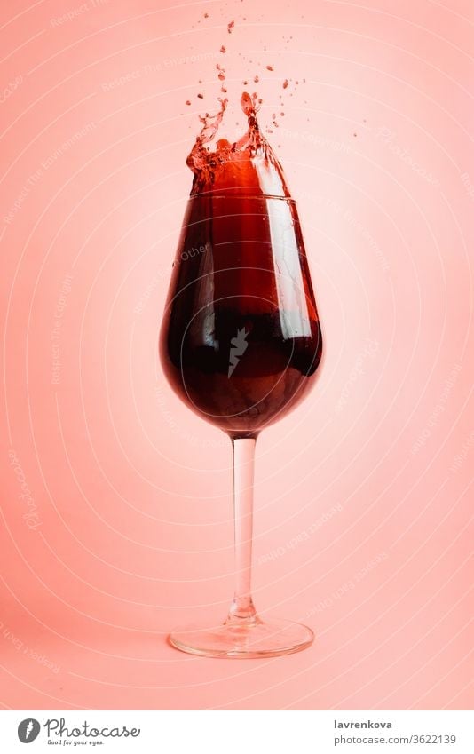 Rotweinspritzer im Glas, dynamisches Bild, selektiver Fokus. Wein Schnaps Gießen Tröpfchen liquide Weingut rot Getränk trinken Feier Alkohol rosa Bewegung