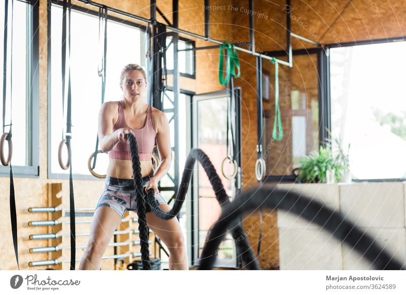 Junge Frau in der Turnhalle beim Crossfit-Training an den Seilen schön Stärke zäh Gerät Fitnessstudio Sport sportlich Ausdauer passen attraktiv Abwechselnd