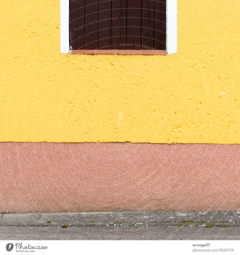 Farbenfrohe mit gelber Farbe gestrichene Hauswand und einem teilweise abgebildeten Fenster. Fassade gelbe Farbe Gebäude Wand Außenaufnahme Menschenleer Mauer