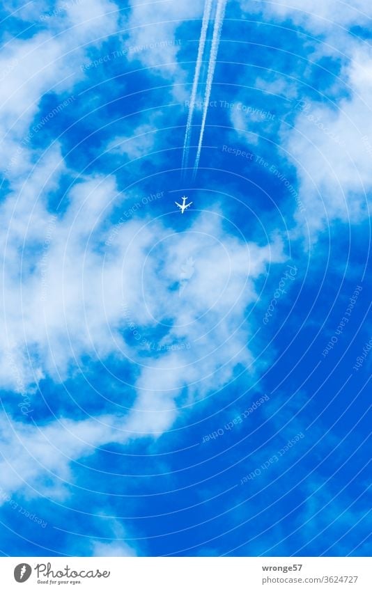 Passagierflugzeug mit Kondensstreifen fliegt hoch oben am leicht bewölkten blauen Himmel Flugzeug hochoben mehrstrahlig Luftverkehr Ferien & Urlaub & Reisen