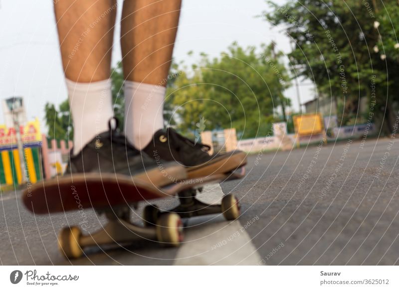 Verschwommene Nahaufnahme der Füße von jemandem, der auf einem Skateboard auf einer leeren Straße fährt. Skateboarding Erholung Lifestyle leere Straßen Sommer