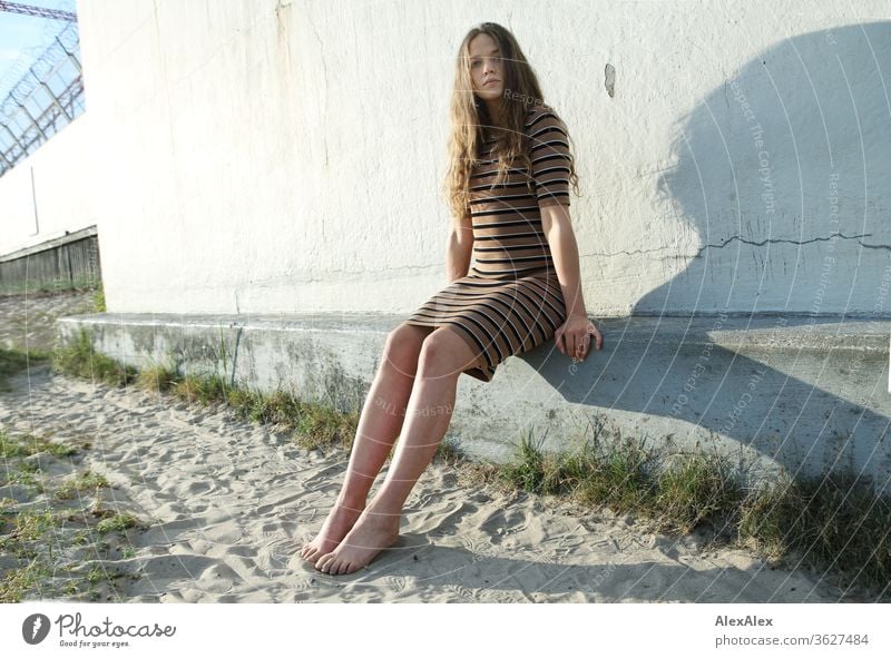 Portrait einer jungen Frau am Strand auf einer Betonmauer intensiv Mädchen Erwachsene Porträt Tag Haut Sonnenlicht selbstbewußt Zentralperspektive Junge Frau