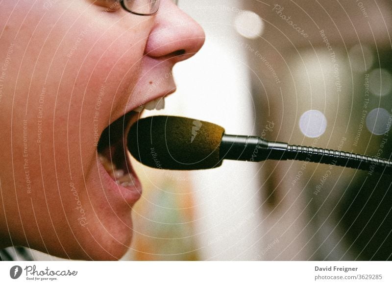 Nahaufnahme Mund eines Schulkindes das in ein Mikrofon schreit bub schule mikrofon laut schreien aufschreien hilferuf wut Angst junge Kindheit Protest pupertät