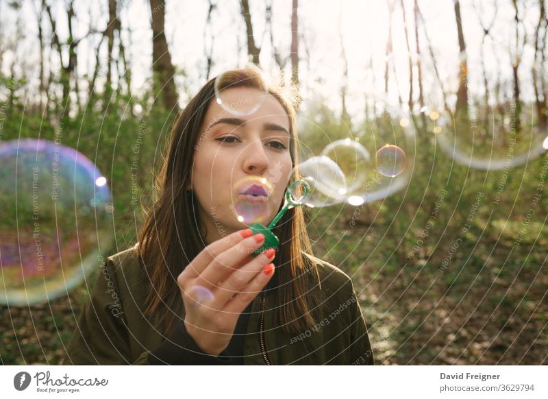 Junge Frau, die im Wald Seifenblasen bläst. Freiheit Blasen blasend Vernetzung Frauen Schlag Menschen Glück nachlässig Spaß Seifenblasen blasen Freizeit
