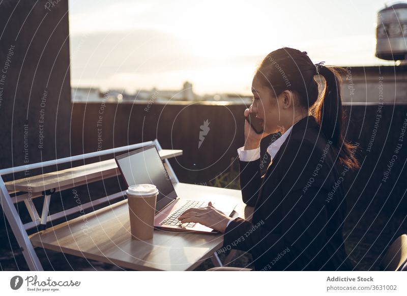 Geschäftige Frau mit Laptop arbeitet auf dem Dach Arbeit Smartphone benutzend reden Geschäftsfrau formal Dachterrasse Gerät Apparatur Business asiatisch jung