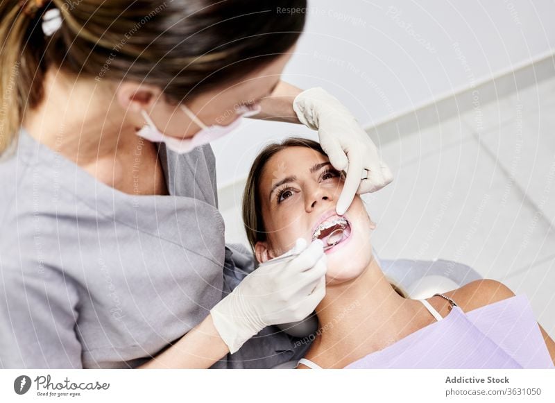 Zahnarzt prüft Zähne des Patienten Frauen geduldig untersuchen Klinik Spiegel Klammer Handschuh Mund geöffnet Arbeit professionell prüfen Zeitgenosse mündlich