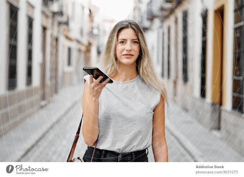 Positive junge Frau mit Smartphone geht auf der Straße Großstadt benutzend Glück Stil Nachricht Spaziergang Browsen Mobile Telefon Lifestyle Gerät Apparatur
