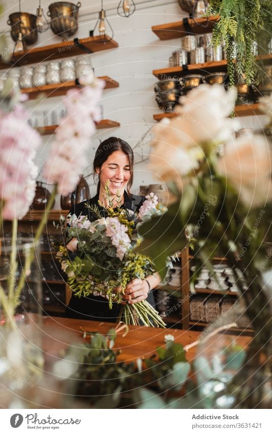 Fröhliche Floristin mit Blumenstrauss arbeitet im Geschäft Floristik Frau Blumenstrauß einrichten kreieren Glück Blütezeit heiter komponieren Designer dekorativ