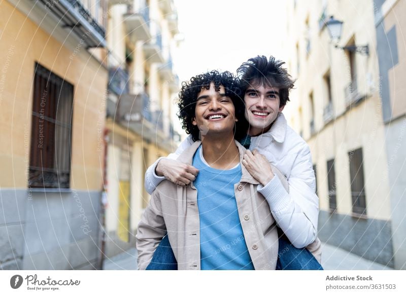 Schwules Paar mit multirassischen Inhalten hat Spaß auf der Straße schwul Huckepack Spaß haben Homosexualität Umarmung Zusammensein lgbt Partnerschaft