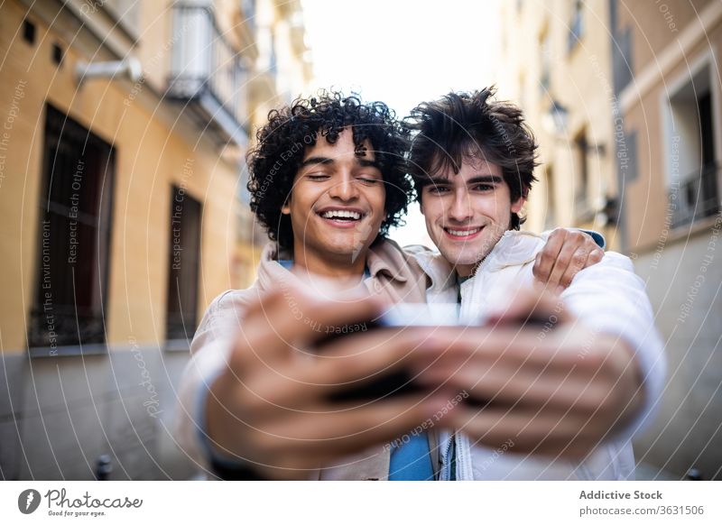 Fröhliches homosexuelles Paar nimmt Selbstliebe am Smartphone Homosexualität Selfie Umarmung schwul Zusammensein Straße lgbt Handy benutzend rassenübergreifend