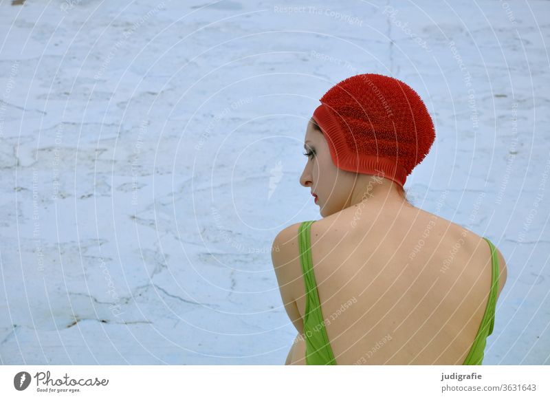 Das Mädchen mit der schönen roten Badekappe und grünem Badeanzug sitzt im leeren Nichtschwimmerbecken. Eine Sommerliebe. Frau Badebekleidung Badehaube Haut jung